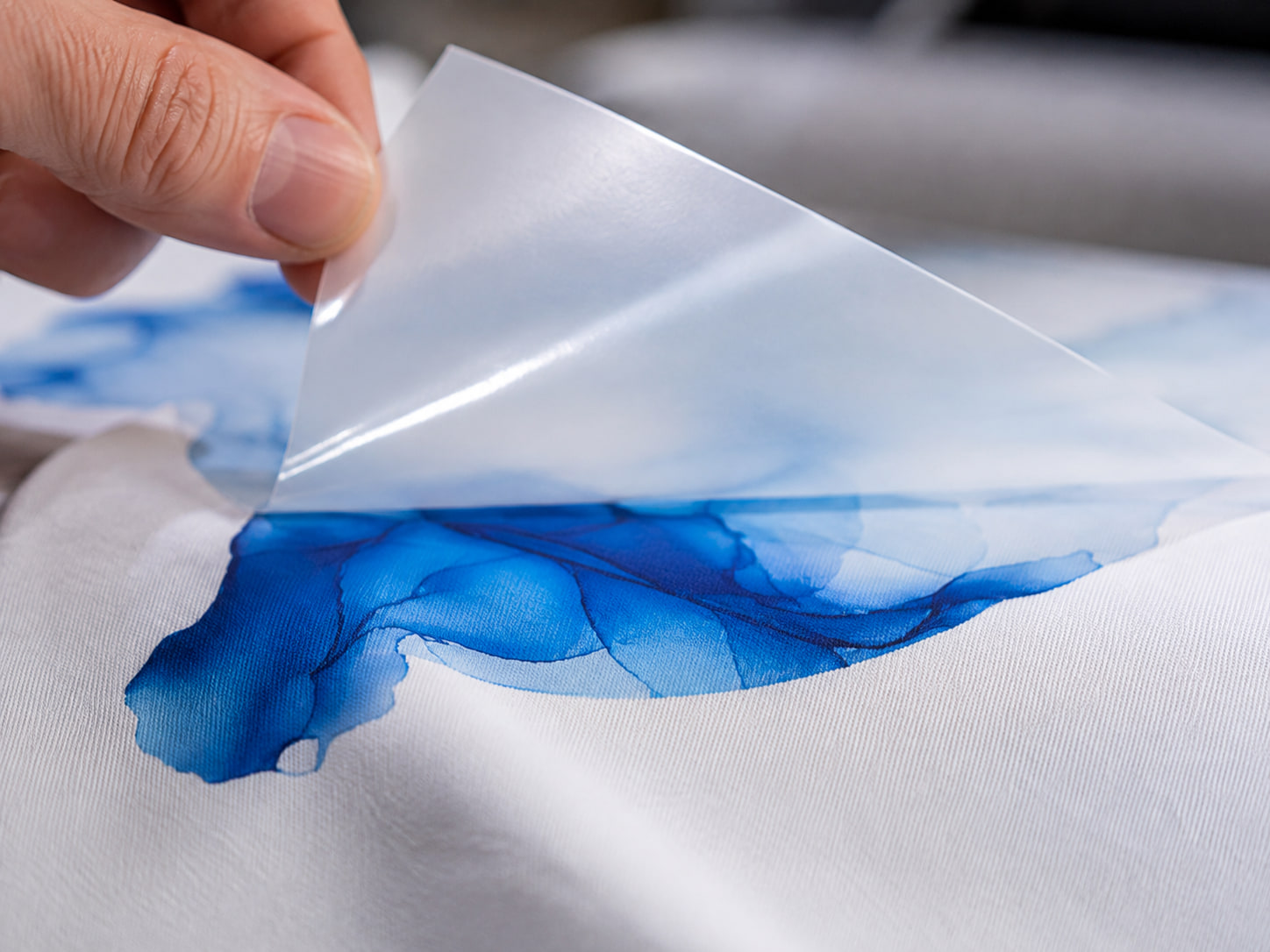 DTF-Transferfolie wird von Hand auf ein bedrucktes Textil gepresst